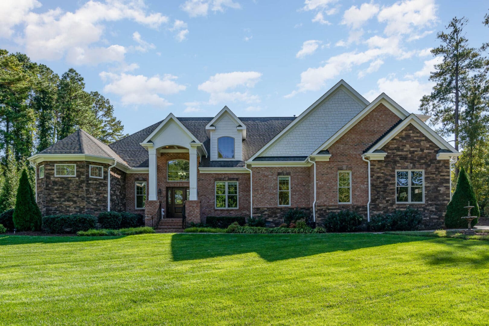 A large brick house with green grass in front of it.